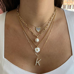 Layered 14k gold chain necklaces with heart, pearl and diamond initial charms worn on model